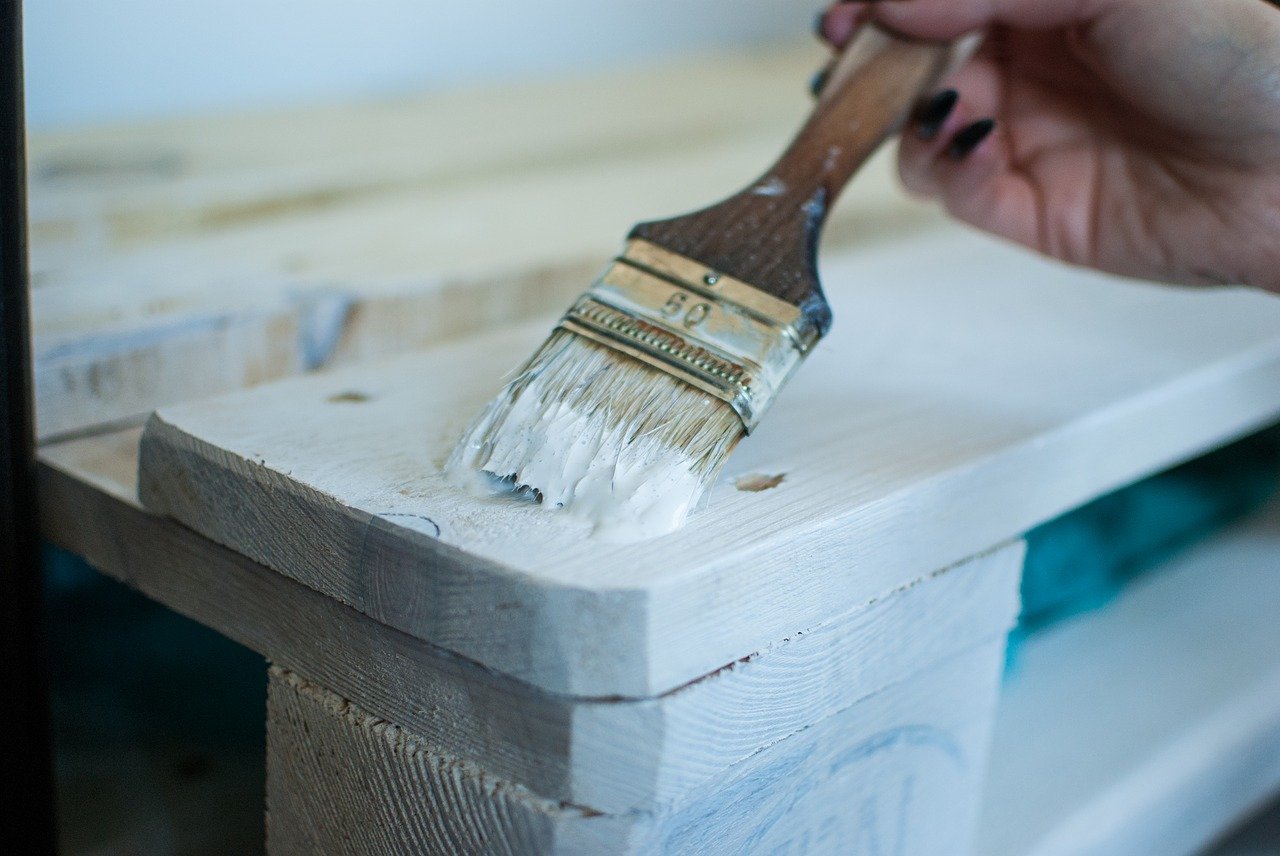 Image of someone painting wood white