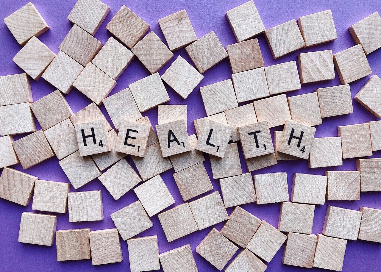 Scrabble letter set out spelling H-E-A-L-T-H on a purple background and overturned scrabble letters